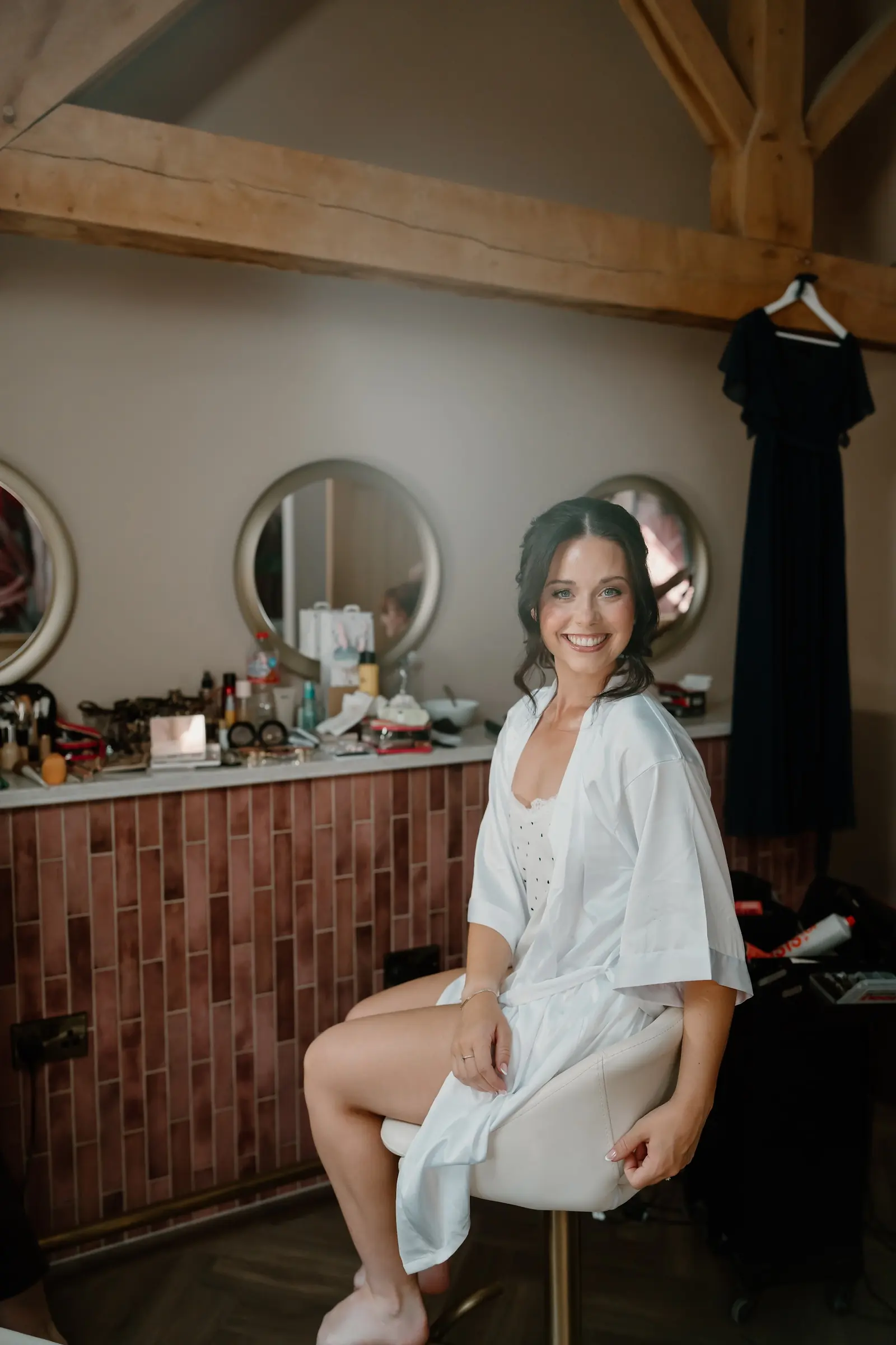 A bride getting ready at the mirrors in the prep room