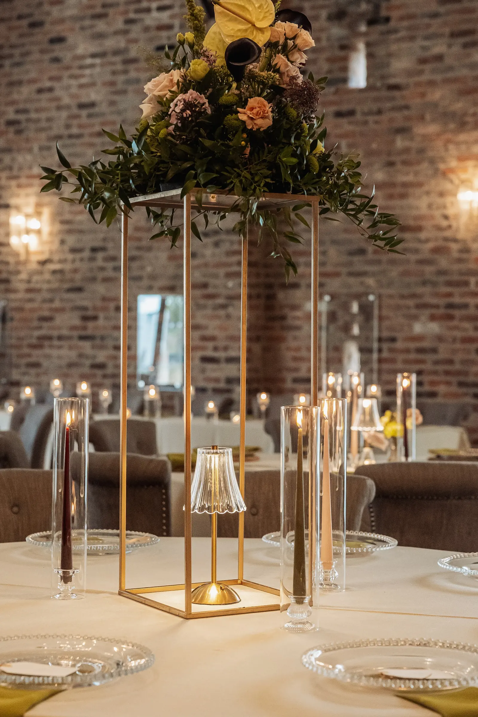 A tall gold centrepiece with flowers and candles