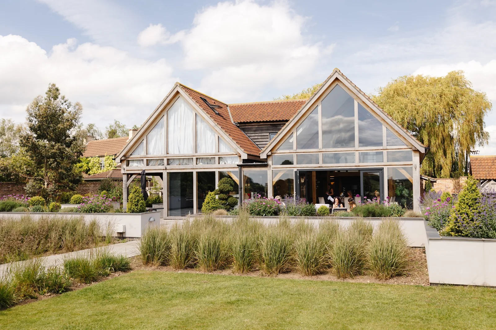 The glass gables of The Oakwood across the lawn and summer planting