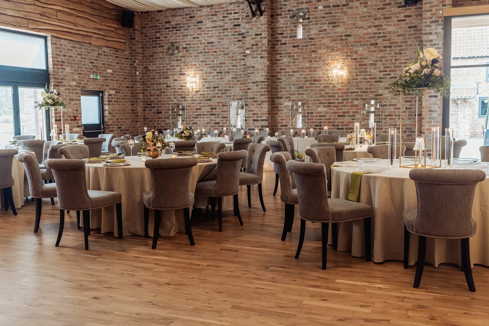 Round tables laid in the Old Grain Store against reclaimed brick walls