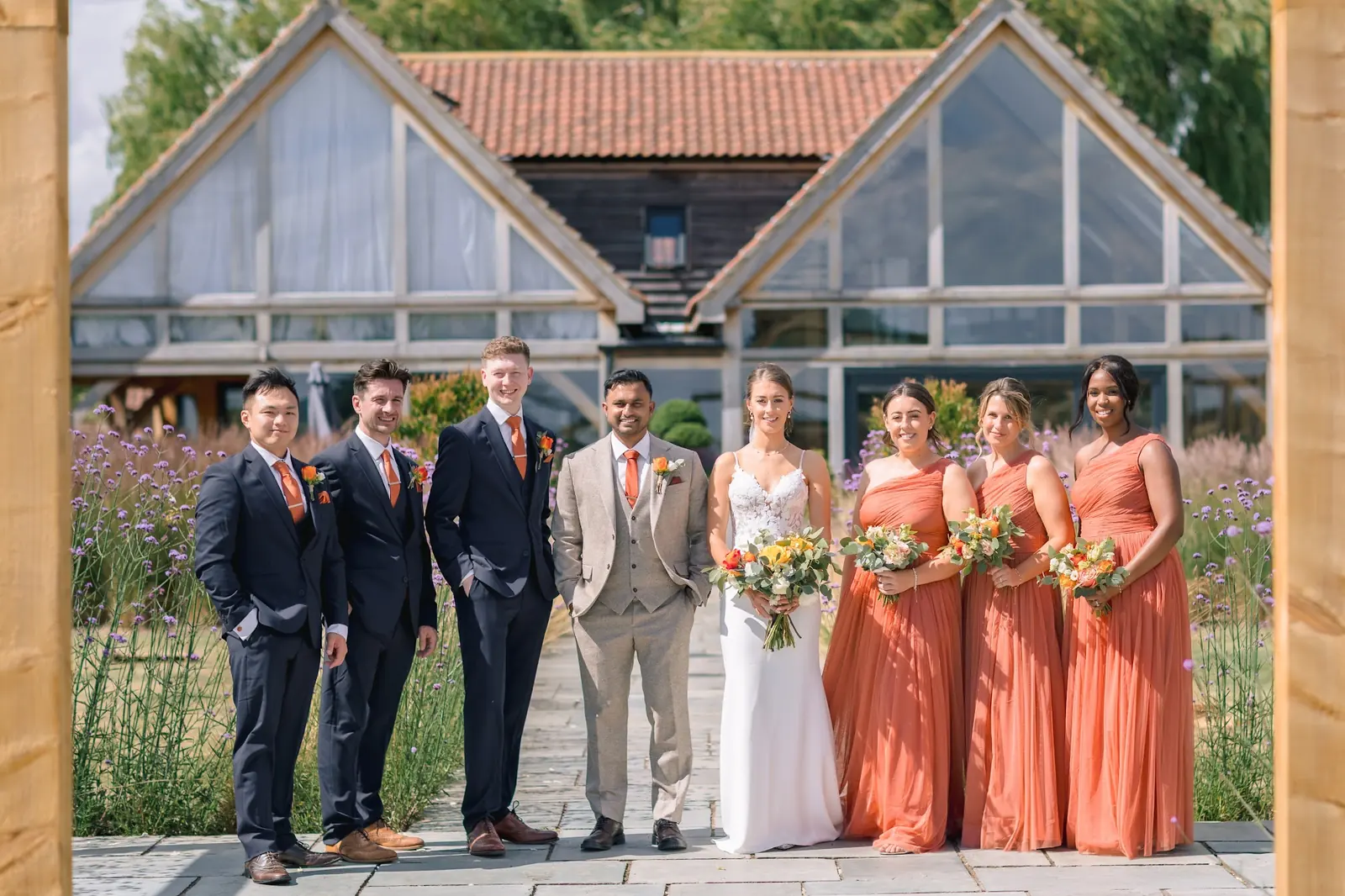 A bridal party in front of the glass gables and lavender