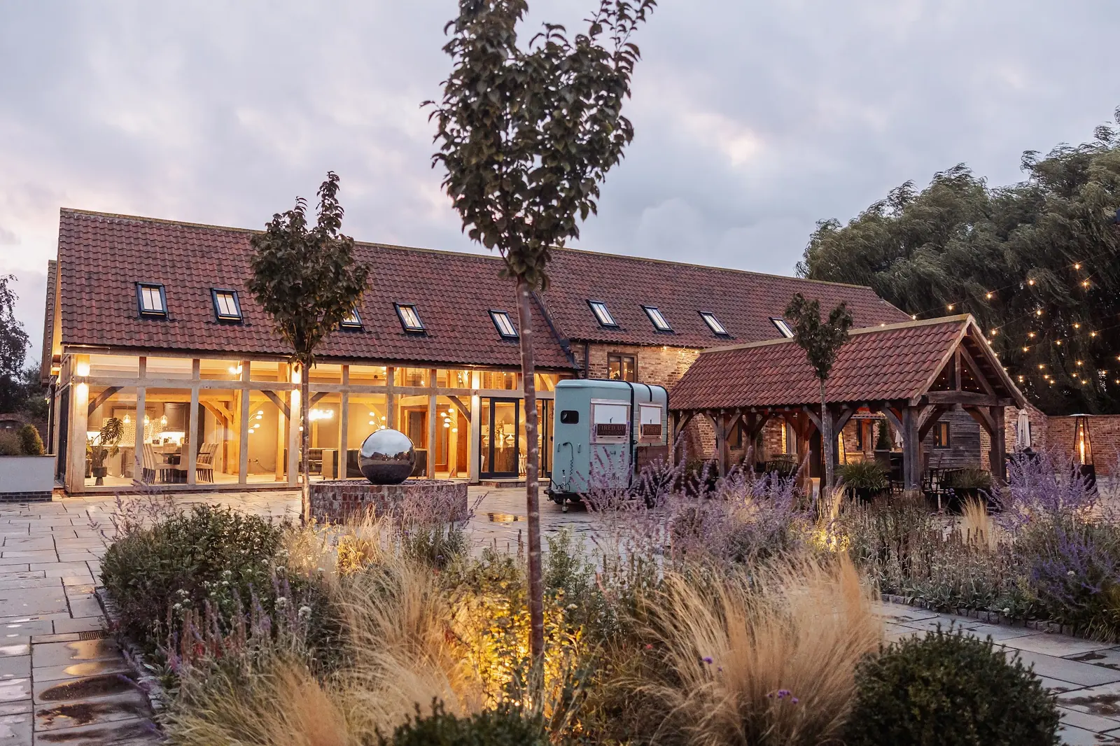 The Oakwood at dusk, lights on, with ornamental grasses in the foreground