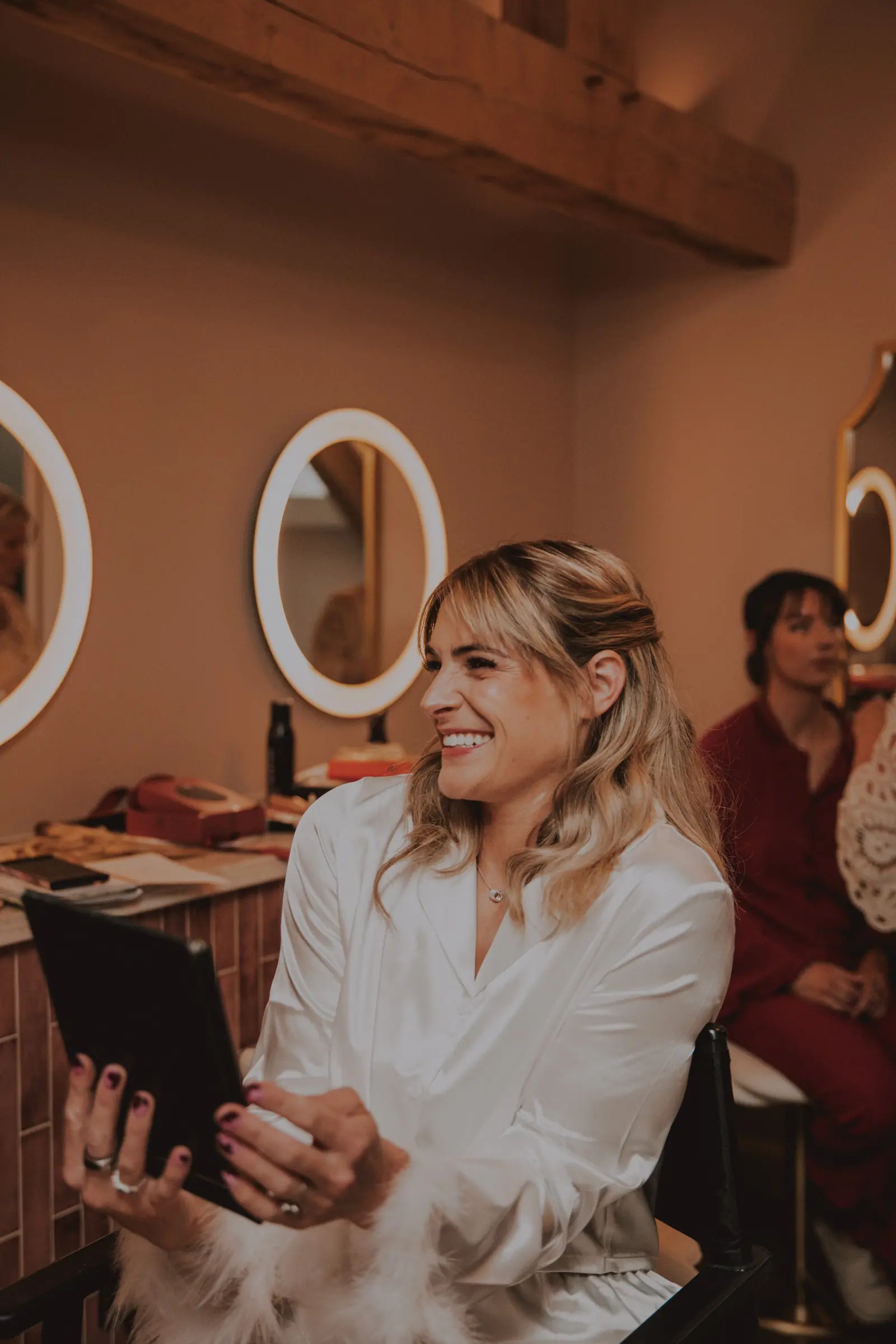 A bride laughing as she gets ready in the prep room