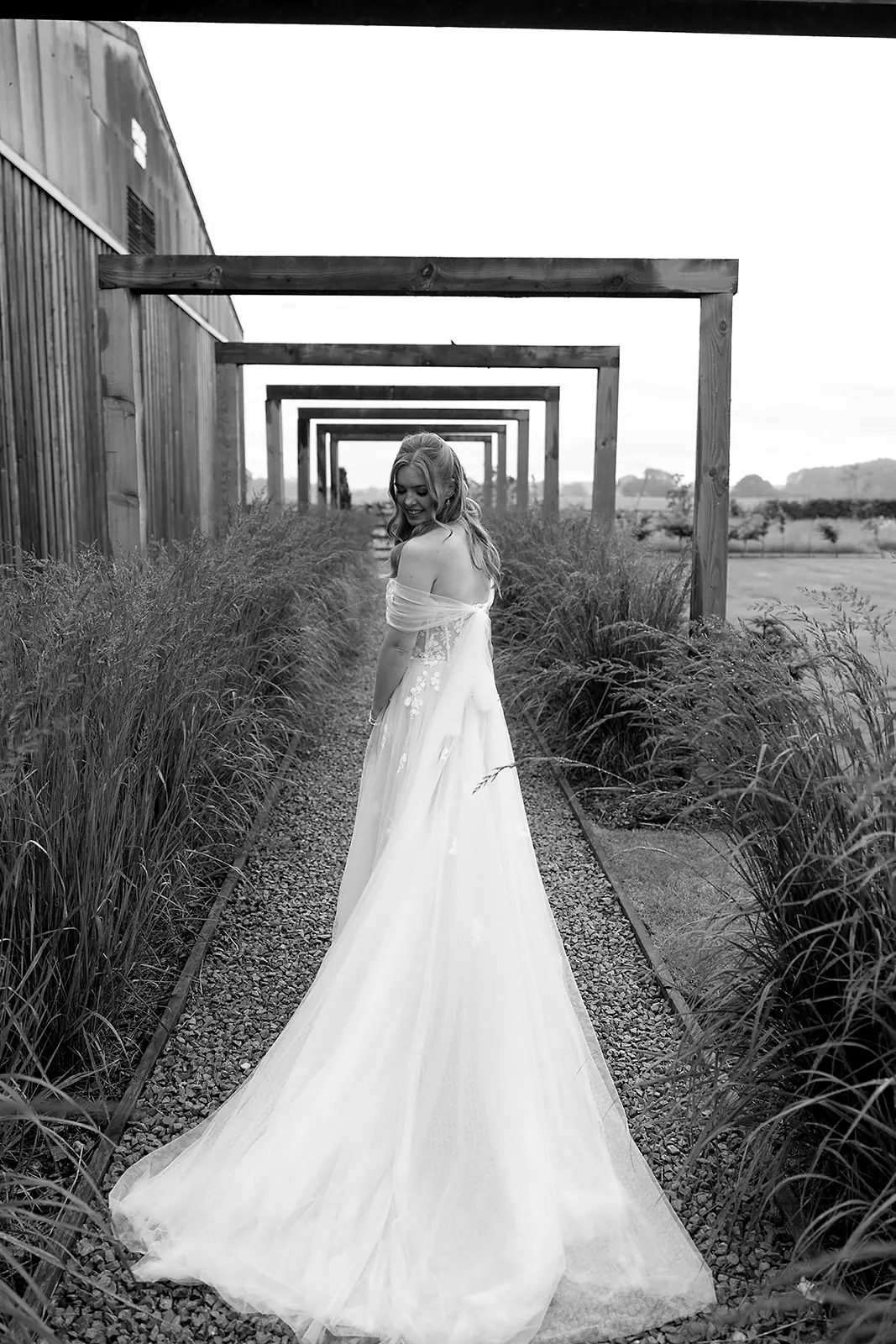 A bride walking through the timber frames, in black and white