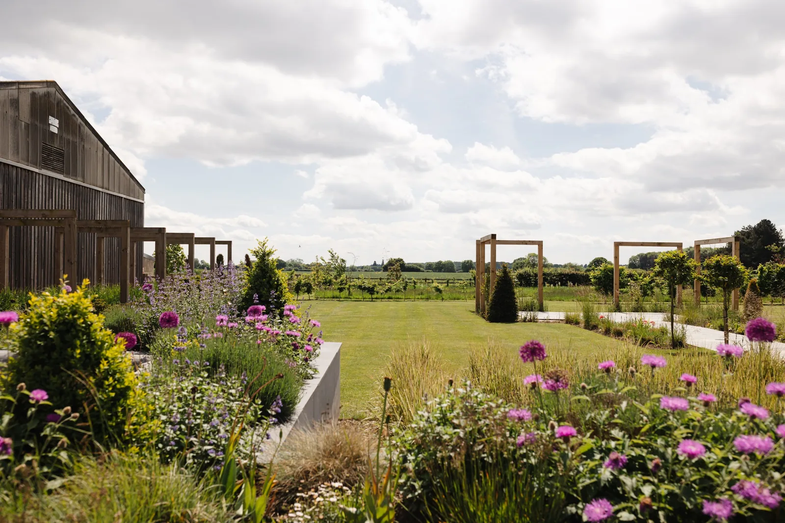 The gardens beyond the barns, with timber frames and the meadow in the distance
