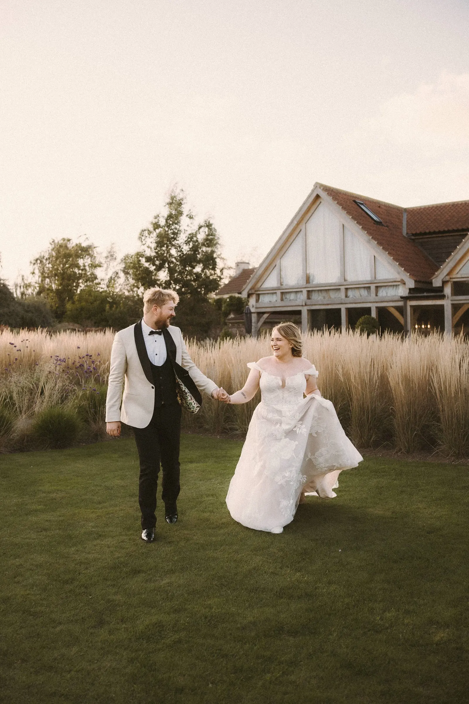 A couple walking through long meadow grass towards the house