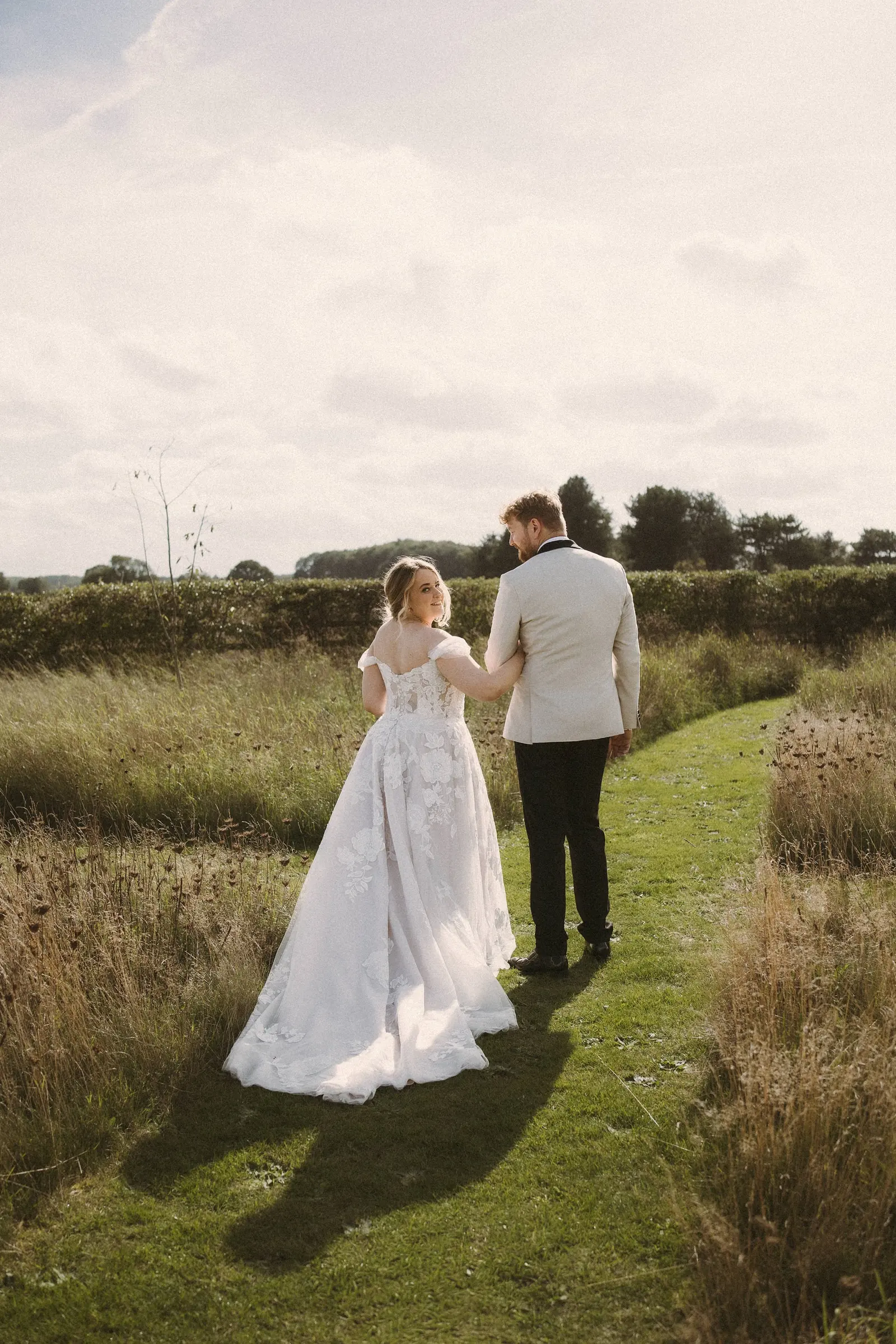A couple walking away through the meadow at golden hour