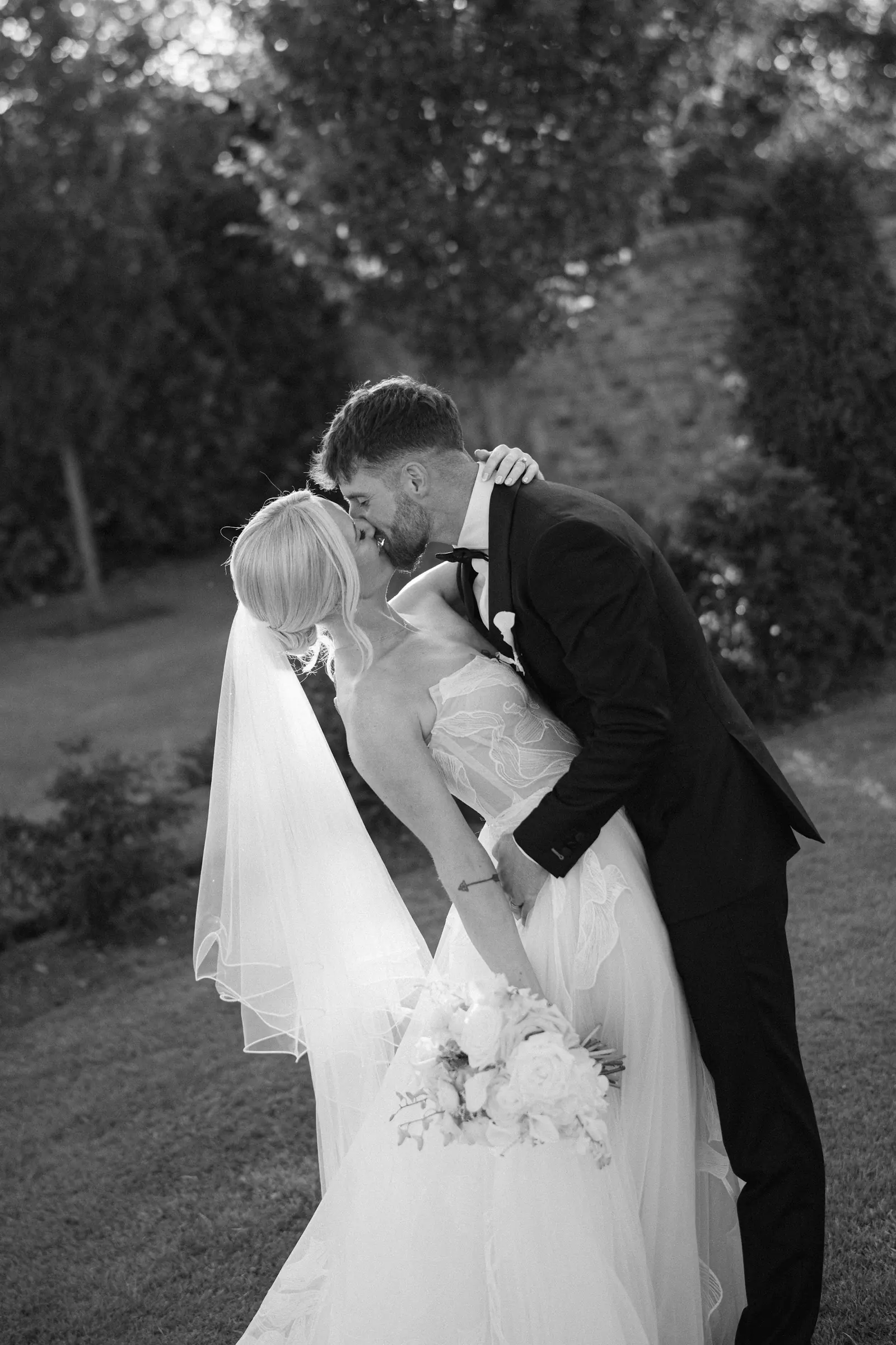 A couple sharing a kiss among the trees, in black and white