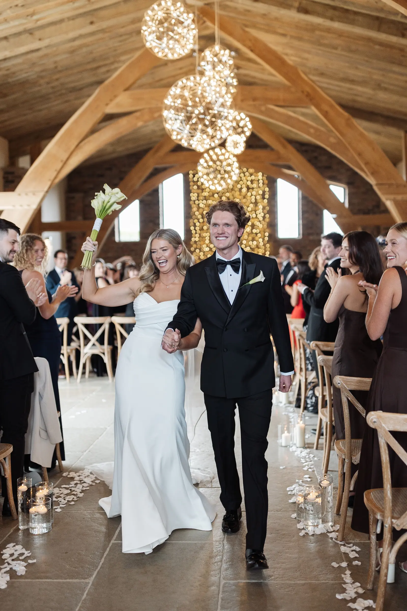 A couple walking back up the aisle under the chandelier