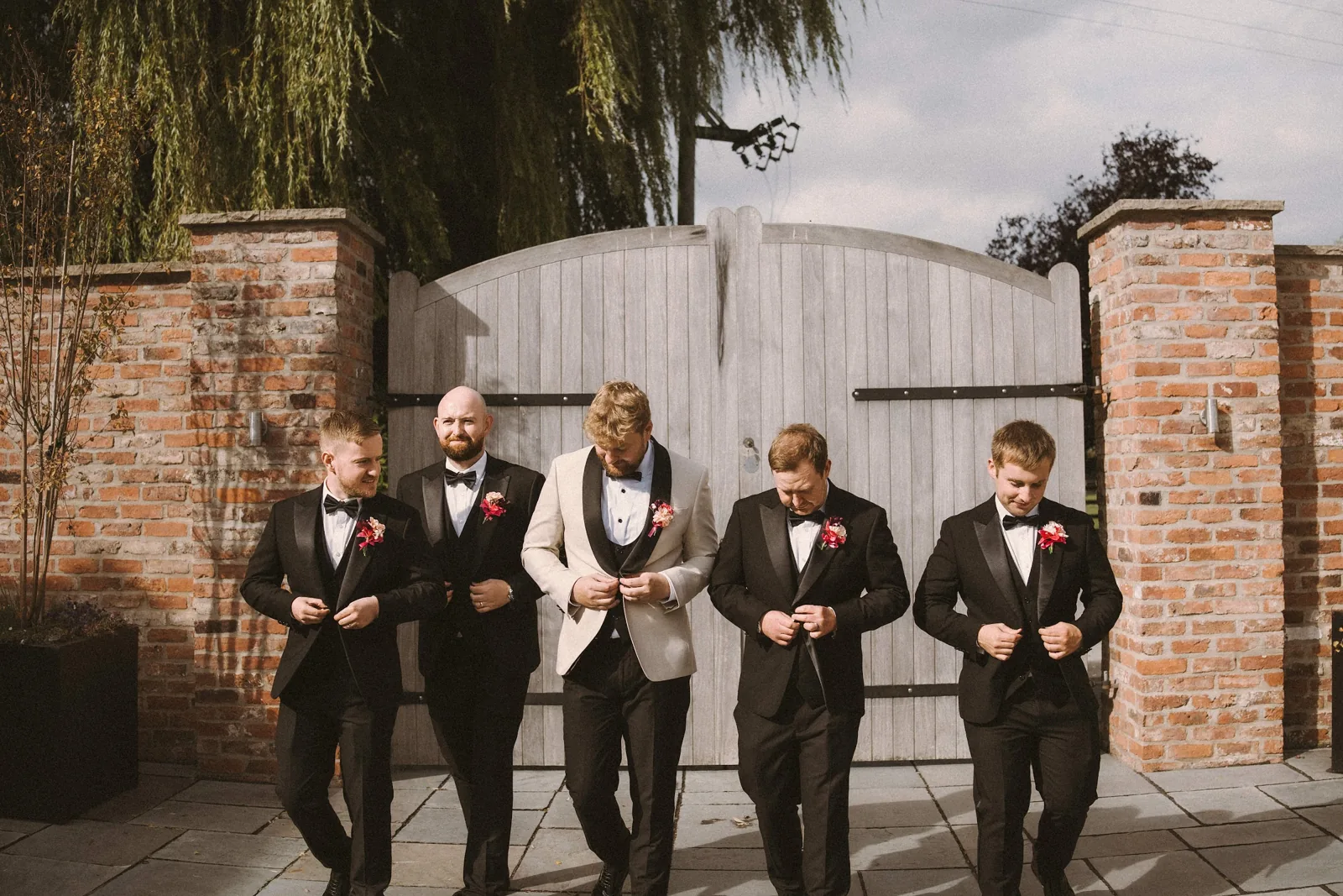 The groomsmen in front of the wooden courtyard gates