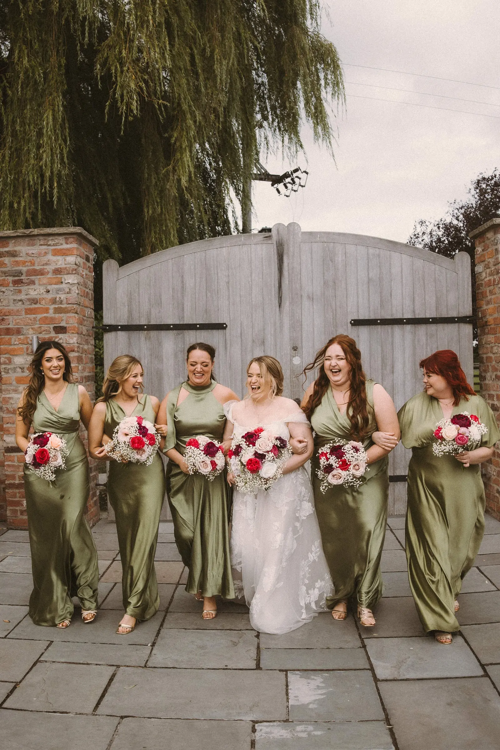 Bridesmaids in sage green in front of the courtyard gates