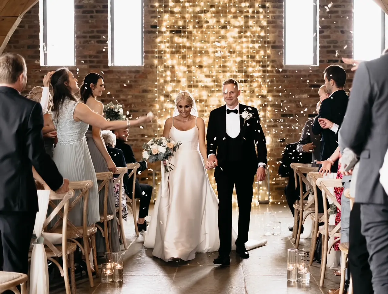 Guests throwing confetti as a couple walk the aisle