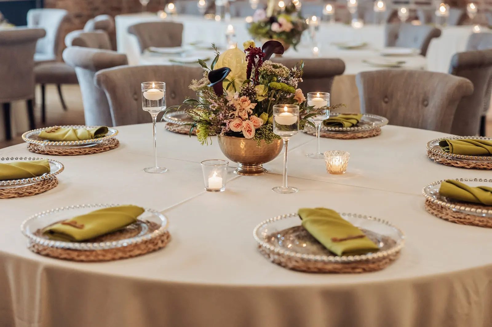 A round table set with gold-rimmed plates and green napkins